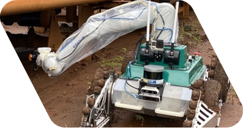 Foto de um lugar externo onde há terra, uma superfície e ferro e, ao centro, o ROSI, robô para serviços de Inspeção.