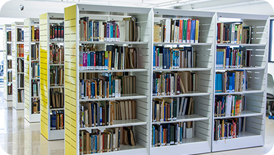 A yellow and white bookshelf filled with books. There are another four shelves behind it.