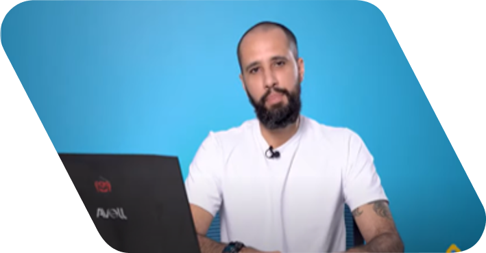 Homem pardo careca olhando para a câmera. Ele usa uma camisa de cor verde clara e está na frente de uma parede azul.