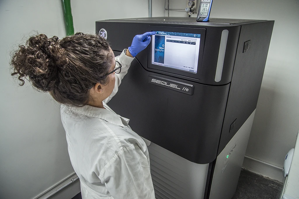 Pesquisadora da Vale utilizando um sequenciador de DNA ou similar, representando o uso de tecnologia avançada em pesquisa.